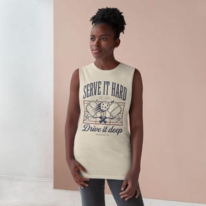 Peut inclure: Débardeur crème avec le texte bleu marine "SERVE IT HARD" et "DRIVE IT DEEP". Le t-shirt présente un graphisme de pickleball avec des raquettes et une balle. Le texte "NASHVILLE, TN" est également inclus.