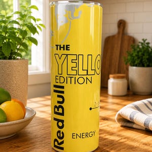 Pode incluir: Um copo cil&iacute;ndrico alto de cor amarela com a marca Red Bull The Yellow Edition em texto preto. O design inclui um gr&aacute;fico de touro prateado no topo, as palavras The Yellow Edition e o log&oacute;tipo Red Bull Energy impresso verticalmente.