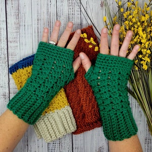 May include: A pair of green crochet fingerless gloves with a textured stitch pattern. The gloves feature a ribbed cuff at the wrist and an opening for the thumb. The design is crafted from yarn, showcasing a consistent pattern throughout the fabric.
