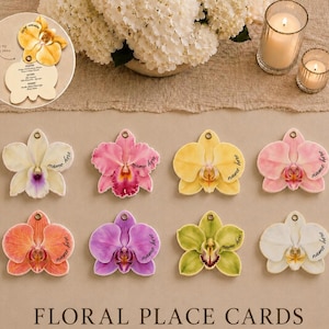 May include: Eight orchid-shaped paper place cards in various colors including white, pink, yellow, orange, purple, and green. Each card features a small hole at the top and the printed text name here. An inset shows the card opening to reveal menu text.