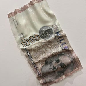 Può includere: Un'opera d'arte bianca e beige che assomiglia a una banconota da 1000 lire. L'opera presenta il testo "1000" e "BANCA D'ITALIA", insieme a un ritratto e altri dettagli. I bordi hanno un design ondulato e strutturato.