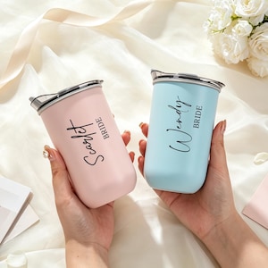 May include: Two stainless steel tumblers with lids, one in matte pastel pink and one in matte light blue. The pink tumbler features the black text "Scarlet" and "BRIDE," while the blue tumbler features the black text "Wendy" and "BRIDE."