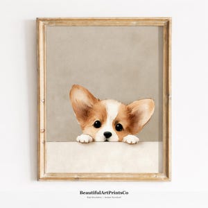 以下が含まれることがあります： 縁から顔を覗かせる茶色と白のコーギーの子犬の水彩画イラストが描かれた額入りアートプリント。子犬は大きな耳、暗い色の目、黒い鼻をしており、金色のフレームの中に無地のベージュの背景で表現されています。