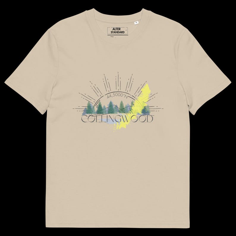 Pode incluir: Uma t-shirt bege de manga curta com um gr&aacute;fico de uma floresta, um sol nascente e o texto "COLLINGWOOD" com "44.5000&deg;N" acima. O design inclui um detalhe de pincelada amarela. A etiqueta interna diz "ALTER STANDARD".