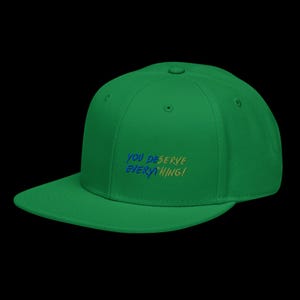 May include: A bright green baseball cap featuring embroidered text on the front panel that reads YOU DESERVE EVERYTHING! The lettering is rendered in a combination of blue and yellow thread, set against the solid green fabric of the cap.