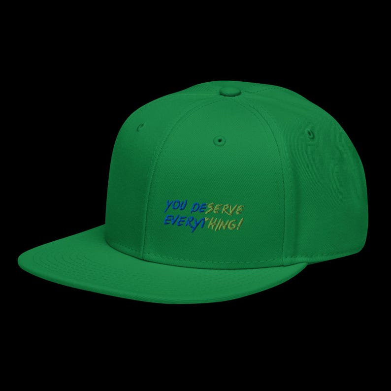 May include: A bright green baseball cap featuring embroidered text on the front panel that reads YOU DESERVE EVERYTHING! The lettering is rendered in a combination of blue and yellow thread, set against the solid green fabric of the cap.