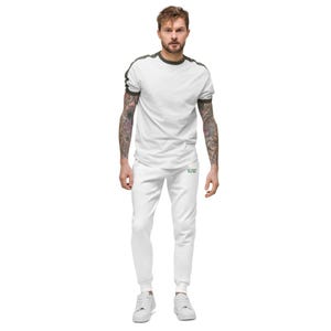 May include: A white t-shirt with dark green trim on the collar and sleeves, paired with matching white joggers. The joggers feature small green text on the upper thigh area. The outfit is completed with plain white trainers.