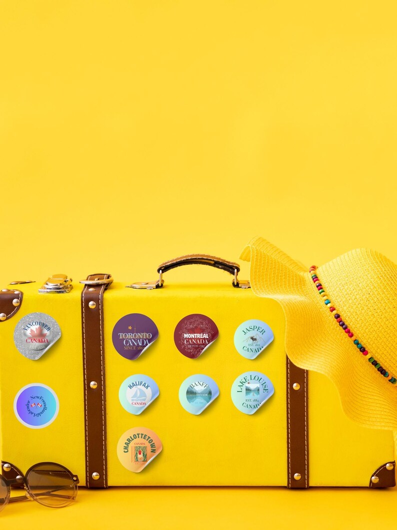 12 Canada cities as glitter pin badges - transparent PNG + printable A4 sheet. Print at home on sticker paper, cut, and use for suitcases, journals, laptops, water bottles. Stickers are on a yellow suitcase. Designed by Alter Standard
