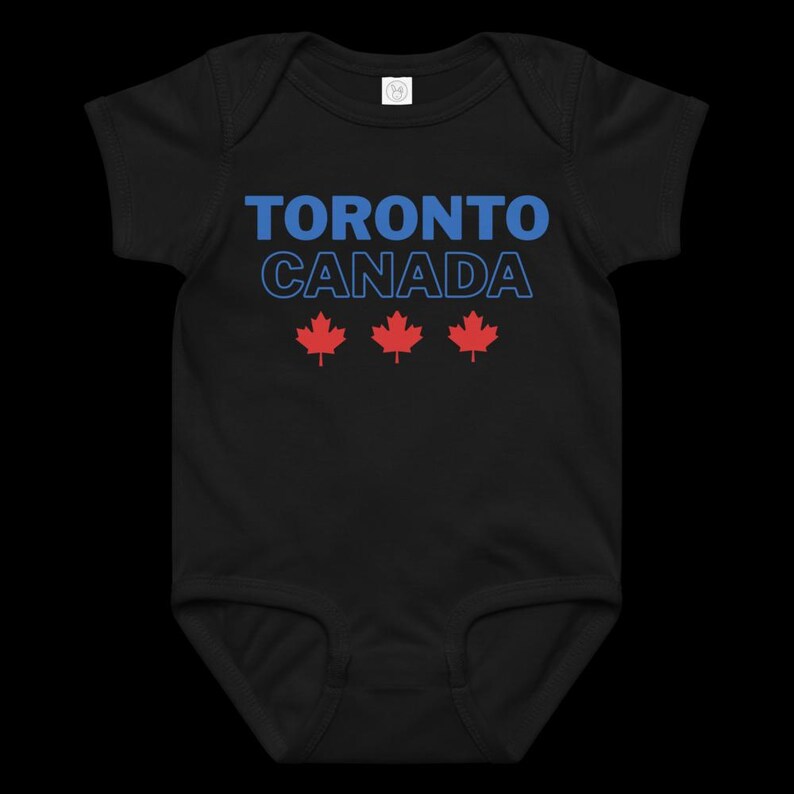 以下が含まれることがあります： 黒の半袖ベビー用ボディスーツ。青い文字で「TORONTO」、青い輪郭のフォントで「CANADA」と書かれ、その下に赤いカエデの葉のアイコンが3つ横一列に並んでいます。この衣服は丸首のデザインです。