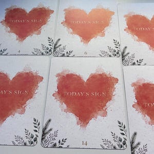 May include: A collection of rectangular cards featuring a watercolour-style red heart in the centre. Each card displays the text "TODAY'S SIGN" in gold lettering within the heart, accompanied by small black botanical illustrations at the bottom corners.