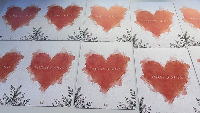 May include: A collection of rectangular cards featuring a watercolour-style red heart in the centre. Each card displays the text "TODAY'S SIGN" in gold lettering within the heart, accompanied by small black botanical illustrations at the bottom corners.