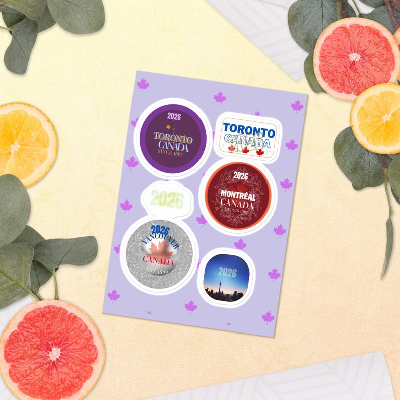 May include: A light purple sticker sheet featuring small maple leaf icons and six distinct stickers. The designs include text for Toronto, Montreal, and Vancouver, Canada, with the year 2026, alongside a skyline image and a plain 2026 label.