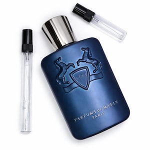 May include: A blue perfume bottle with a silver cap and two sample vials. The bottle features a shield design with two horses and the text "1743". The words "PARFUMS de MARLY PARIS" are printed on the bottle.