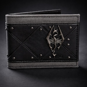 May include: Black bi-fold wallet with a silver emblem and studded accents. The wallet features a gray fabric trim and a diamond pattern on the front. The emblem is a stylized dragon.