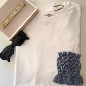 May include: A white ceramic mug with a black handle and the text "But First, Coffee" in a black, bold font. The mug is on a white surface.