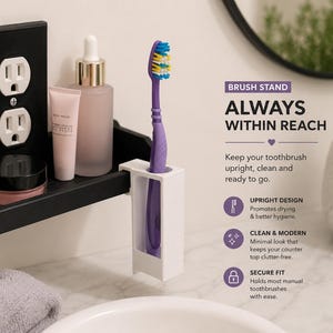 May include: A white toothbrush holder with a purple toothbrush. The holder is on a black shelf with a black outlet, a pink tube, a clear bottle, and a small jar. Text on the image reads "BRUSH STAND ALWAYS WITHIN REACH."