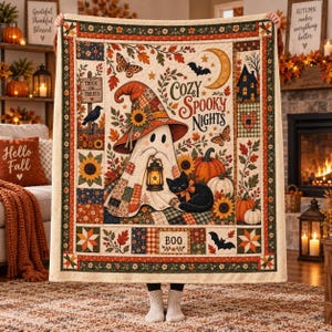 May include: A cream-colored quilt featuring a central ghost wearing a patchwork hat and holding a lantern, accompanied by a black cat, pumpkins, sunflowers, and bats. The text reads Cozy Spooky Nights, Trick or Treats, and Boo, with autumn-themed borders.