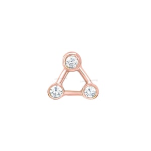 May include: A rose gold triangle stud earring with three clear, round-cut cubic zirconia stones. The stones are set in bezel settings, and the earring has a polished finish. The design is minimalist and modern.