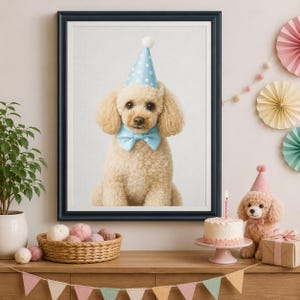 May include: A framed wall art print featuring a light brown poodle wearing a light blue polka dot party hat and a matching light blue bow tie. The poodle is centered in the frame, looking forward against a plain, light-colored background.