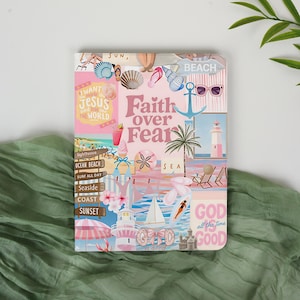 May include: A journal with a collage design featuring beach-themed illustrations and the text "Faith over Fear." The design includes seashells, a lighthouse, sunglasses, and the words "God is good."