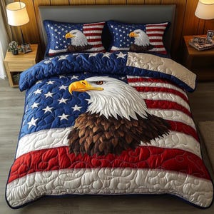 Könnte beinhalten: Eine gesteppte Tagesdecke und zwei Kissenbezüge mit einem amerikanischen Flaggenmuster und einem detaillierten Weißkopfseeadler. Die Tagesdecke hat ein blaues Feld mit weißen Sternen, rot-weißen Streifen und einem großen Adler.
