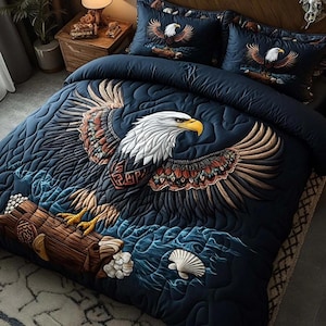 Könnte beinhalten: Marineblaues Bettwäsche-Set mit einem bestickten Design eines Weißkopfseeadlers mit ausgebreiteten Flügeln. Der Adler hat einen weißen Kopf, einen gelben Schnabel und braune und rote Flügelfedern. Das Set beinhaltet einen Bettbezug und zwei Kissenbezüge.