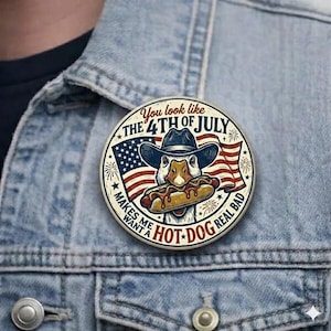 May include: A round pin with a duck wearing a cowboy hat and holding a hot dog. The pin has the text "You look like the 4th of July" and "Makes me want a hot dog real bad" with an American flag design.