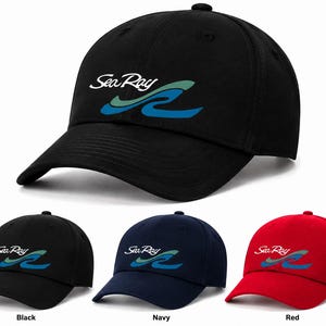May include: A collection of three baseball caps in black, navy, and red. Each cap features the white text Sea Ray above a stylized wave graphic in light green and blue. The caps have a structured crown, a curved brim, and a button on top.