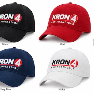 以下が含まれることがあります： 黒、赤、ネイビーブルー、白の4つの野球帽。それぞれにKRON 4 San Franciscoのロゴが白、黒、赤の文字でデザインされています。円形のインセット画像は、生地の熱転写プリントの詳細をクローズアップで示しています。