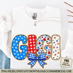 May include: White sweatshirt with the word "GIGI" in a patriotic design. The letters feature blue stars, red plaid, and floral patterns, with a blue gingham bow. A silver necklace with a pendant is also visible.