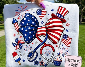May include: White sweatshirt featuring a patriotic design with a large bow in red, white, and blue, a stethoscope, and various American flag-themed elements. Includes fireworks, stars, a cupcake, and the text "PNGS DIGITAL DOWNLOAD".