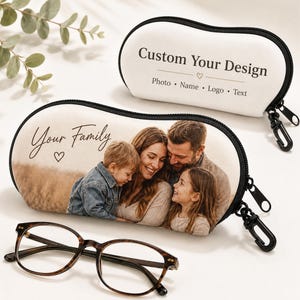 May include: Two oval-shaped zippered eyeglass cases with black trim and clips. One case features a printed family photograph with the text "Your Family" and a heart icon. The other case is white with the text "Custom Your Design" and "Photo • Name • Logo • Text".