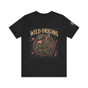 Könnte beinhalten: Schwarzes T-Shirt mit einem farbenfrohen Grafikdesign eines Planeten, der mit Pflanzen bedeckt ist, und dem Text "WILD ORIGINS" in goldfarbenen Buchstaben. Das Design enthält Weltraumelemente. Das T-Shirt hat einen Rundhalsausschnitt und kurze Ärmel.