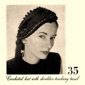 以下が含まれることがあります： 肩まで届く長いタッセルが付いた黒いクロシェハット。暗い髪と黒いトップスを着た人が被っています。