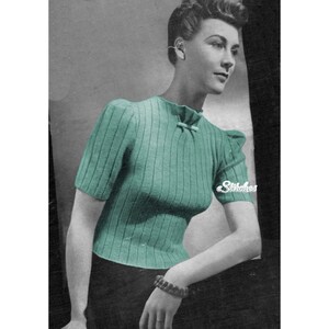 May include: A vintage knitting pattern for a green short-sleeved sweater with a bow detail at the neckline. The pattern is from the 1940s and features a classic, feminine style.