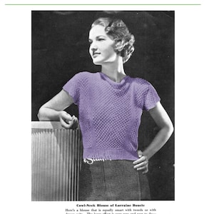 May include: A purple knitted blouse with a cowl neck and short sleeves. The blouse has a lacy texture and is shown on a model.