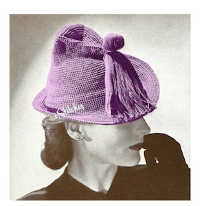 May include: A purple crocheted hat with a tassel. The hat has a unique shape with a pointed crown and a wide brim.