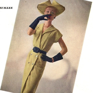 以下が含まれることがあります： ヴィンテージファッションイラスト。薄緑色のドレス、黒いベルトと手袋を身につけた女性。お揃いのベール付き帽子をかぶっています。ドレスはダブルブレストのデザインで大きなボタンが付いています。スタイルは1950年代を彷彿とさせます。