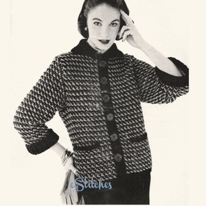 May include: A black and white knitted cardigan with a button-up front and a black collar. The cardigan has a textured pattern and is worn by a woman with dark hair.