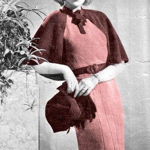 May include: A woman wearing a pink dress with a maroon cape and a maroon hat. She is standing next to a potted plant.
