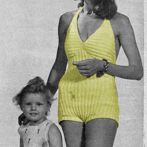 May include: A woman wearing a yellow striped swimsuit with a halter top and a young child wearing a white sleeveless dress. The woman is kneeling and the child is sitting on the ground.