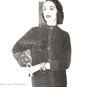 May include: A black and white cardigan with a houndstooth pattern. The cardigan has a high neckline and a button closure. The model is wearing the cardigan with a black skirt.
