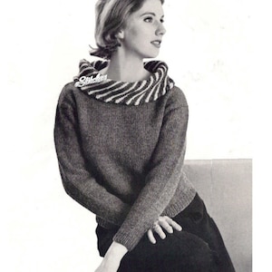 May include: A gray knitted sweater with a wide, striped collar. The collar is black and white.