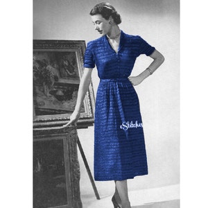 May include: A blue knitted dress with a V-neck and short sleeves. The dress is fitted at the waist and has a slightly flared skirt. The dress is being modeled by a woman standing in front of a painting. The text "eStitches" is visible on the dress.  Directions are given for size 14. Changes for sizes 16 and 18 are in parentheses. MATERIALS: RUBAN D'ART 11 (13-15) spools. Clair