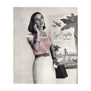 Op de afbeelding: Een vrouw draagt een roze gebreide trui met korte mouwen en een witte rok. Ze houdt een zwarte handtas en een witte papieren tas vast. De achtergrond is een poster die reclame maakt voor reizen naar Los Angeles met de tekst "Los Angeles Fly TWA!"