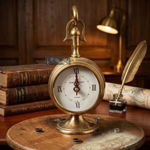 Può includere: Un orologio in ottone in stile vintage con quadrante bianco, numeri romani e la scritta "49 Bow Street London". L'orologio è su un tavolo a bobina di legno, con una penna e un calamaio. Vecchi libri e una mappa sullo sfondo.