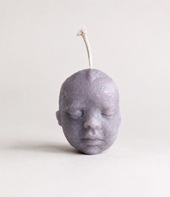 A realistic sculpted baby-head candle that burns from the top — unsettling, darkly funny, and impossible to ignore on any shelf.
