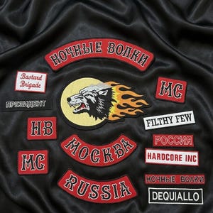 May include: A collection of embroidered patches featuring a central wolf head emblem with flames, surrounded by various text patches including "NOCHNYE VOLKI," "Bastard Brigade," "PRESIDENT," "MC," "FILTHY FEW," "ROSSIYA," "HARDCORE INC," "MOCKBA," "RUSSIA," and "DEQUIALLO."