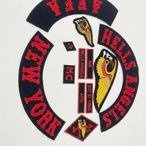 May include: A collection of black and red embroidered patches. The patches include the words "HELLS ANGELS", "NEW YORK", "AFFA", "SGT AT ARMS", and "MC". There are also patches with the number "666" and a winged emblem.