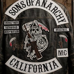 May include: A distressed black leather jacket with multiple patches. The patches include the words "Sons of Anarchy", "California", and a grim reaper holding a rifle. Other patches read "Unholy Ones", "Redwood", "Men of Mayhem", "Original", and "MC".